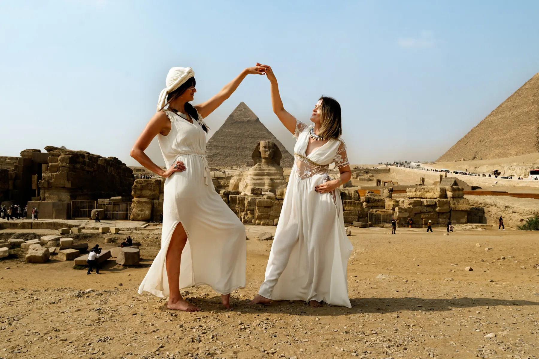 Twee vrouwen in witte jurken dansen bij de piramides van Gizeh